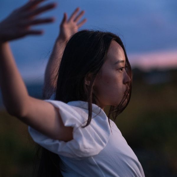 Person stretching outdoors with a serene landscape background.