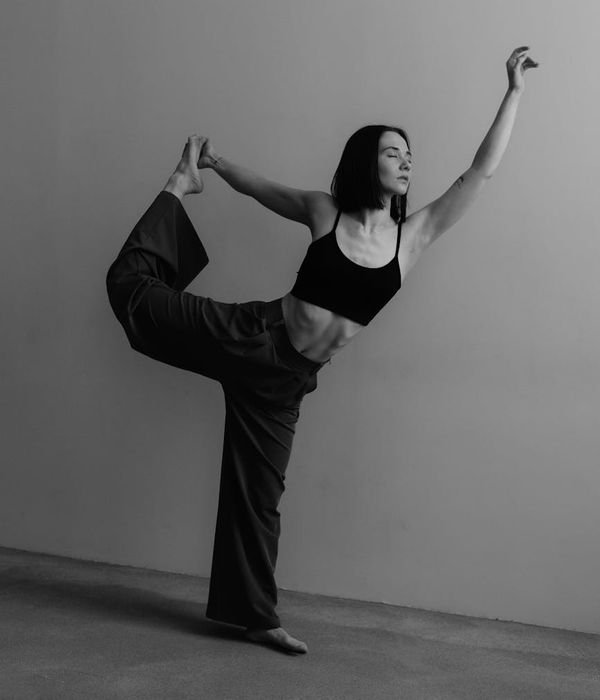 Woman in a graceful yoga pose in a minimal studio.